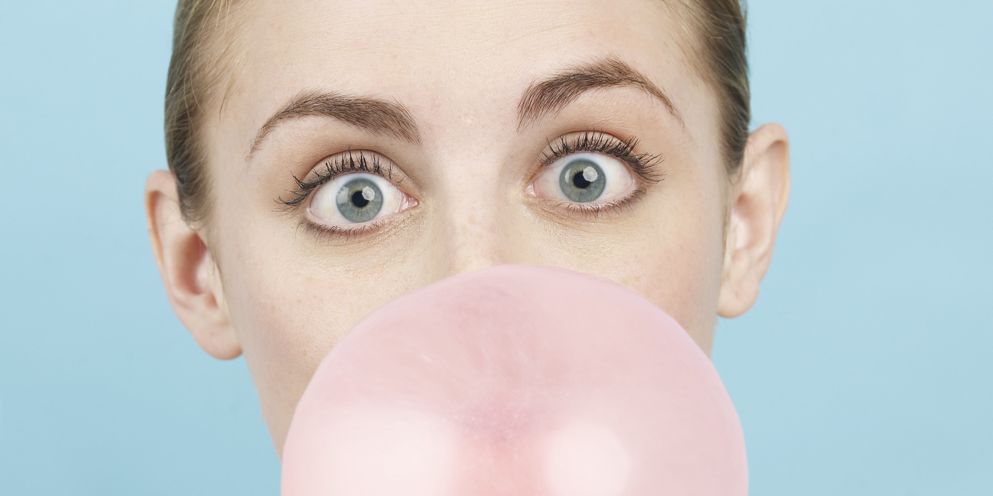 Young woman blowing pink bubble gum bubble, portrait